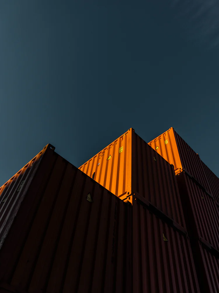 Stacked shipping containers against a deep blue sky
