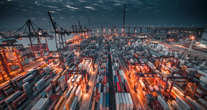 Container port with cranes and stacked shipping containers at dusk