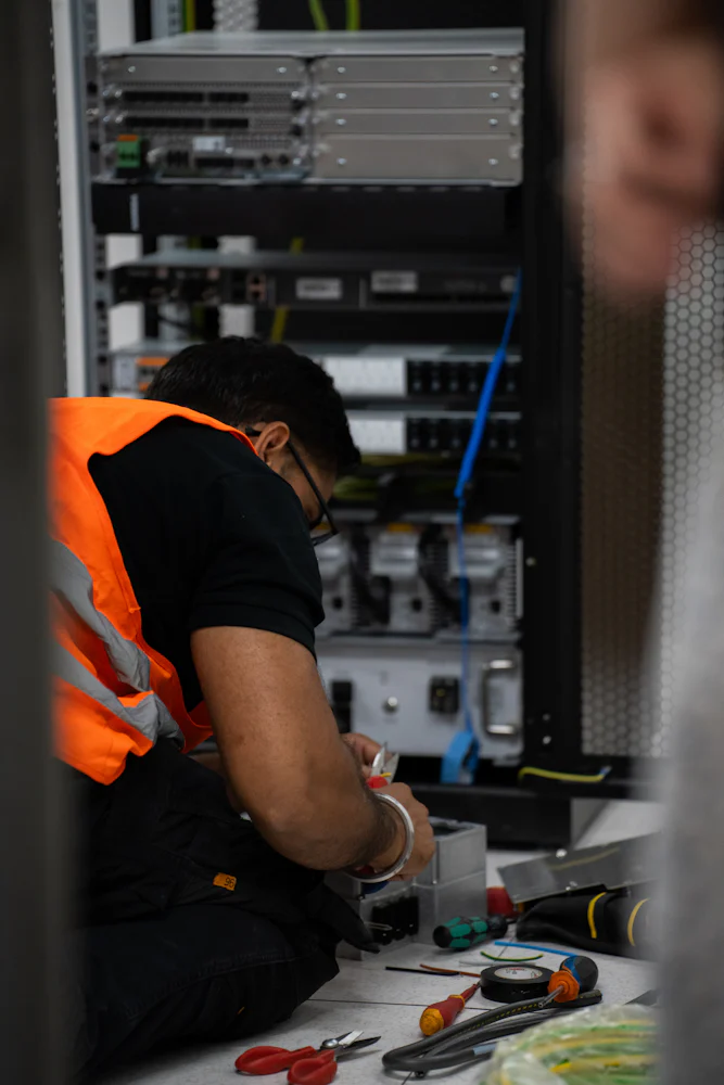 Technician in high-visibility clothing working on server equipment